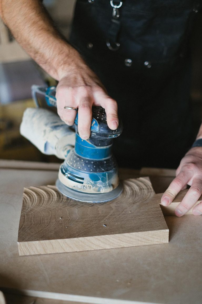 Craftsman using electric sander to polish wood surface