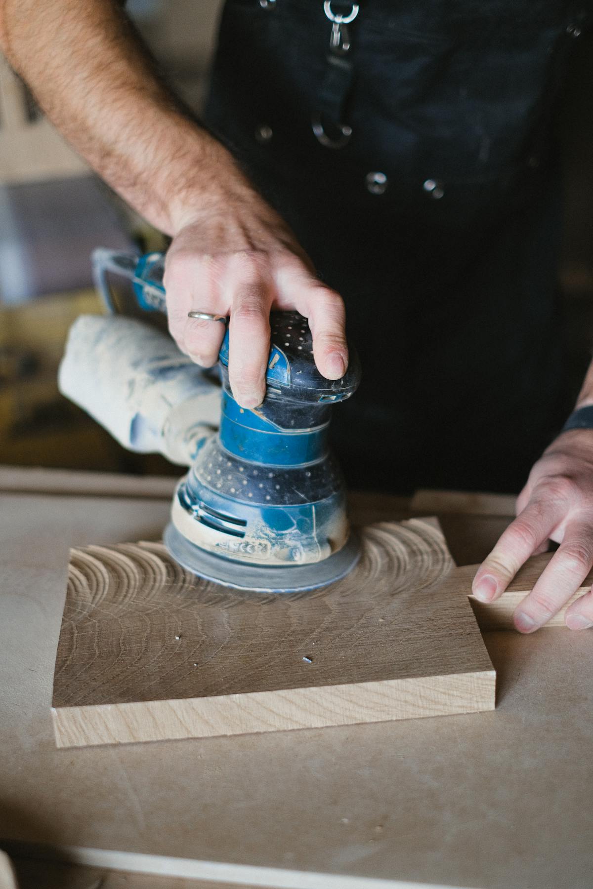 Craftsman using electric sander to polish wood surface