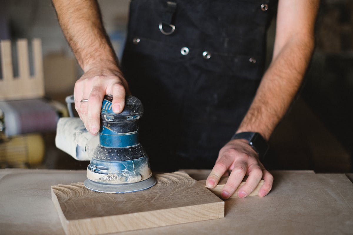 Carpenter using random orbital sander on wood surface