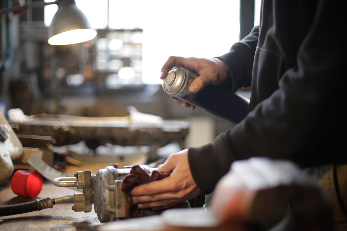 Mechanic using spray for power tool maintenance