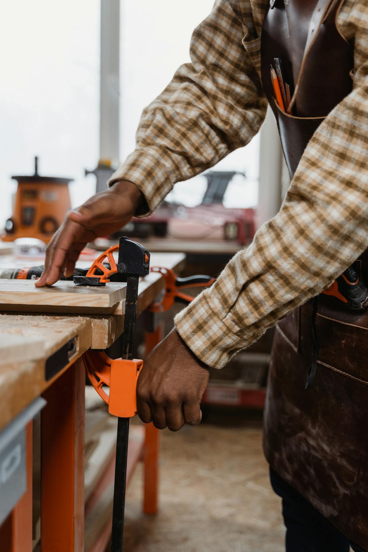 Craftsman using woodworking clamp in workshop